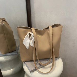 Chic khaki tote bag with silk scarf and gold lettering on a minimalist pedestal
