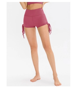 Detail of high-waisted yoga shorts featuring side drawstrings and dark pink stretch fabric
