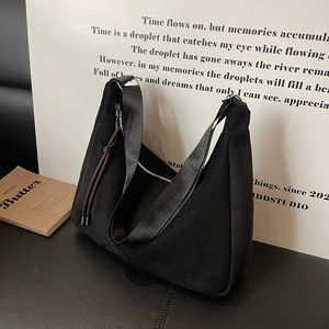 Minimalist black faux suede crescent bag with wide shoulder strap and fringe zipper detail