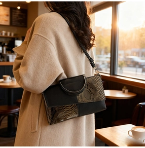 Detail of snake skin texture and metal ring handle on a high-quality women's shoulder bag