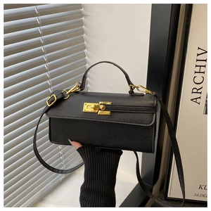 Détail du sac à main en cuir noir avec fermoir rotatif doré et bandoulière fine
