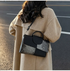 Close-up of luxury snakeskin patchwork handbag with litchi grain leather and metal hooks