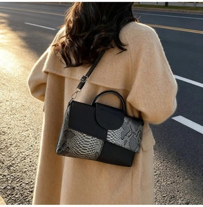 Detail of snake print and black leather patchwork handbag with metallic texture