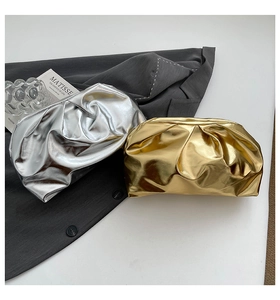 Détail de pochettes plissées dorées et argentées posées sur une veste grise chic