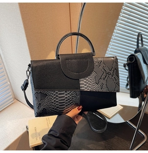 Close-up of snakeskin embossed patchwork and sleek metal handle on the textured handbag