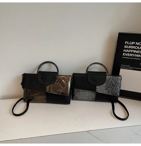 Detail of elegant black handbags featuring snakeskin pattern panels and metal ring handles