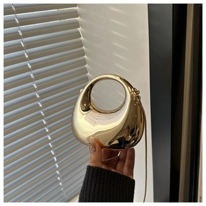 Detailed view of a semi-circular mirror gold metal handbag with a circular hollow handle