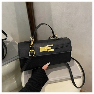 Détail de la texture cuir noir croisé et du fermoir doré sur un petit sac à main chic