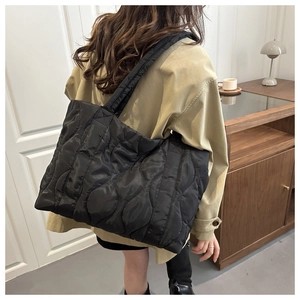 Black quilted nylon tote bag with wave pattern shown on model in modern home setting