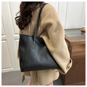 Close-up of minimalist black tote bag with slim shoulder straps and fine stitching