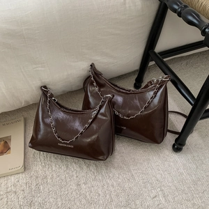 Lot de sacs hobo marron foncé avec chaînes argentées sur tapis blanc, style de vie cosy