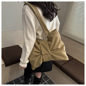 Side view of woman wearing khaki oversized tote bag with large decorative bow detail