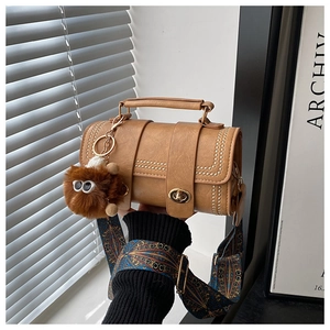 Detail of vintage brown crossbody bag featuring rivet accents and geometric print strap