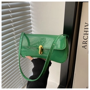 Detail of green patent leather shoulder bag featuring a gold twist-lock and glossy finish