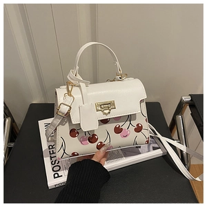 Detail of white leather shoulder bag featuring cherry prints and gold square buckle