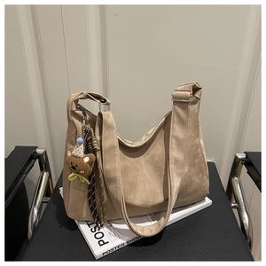 Detail of camel hobo bag featuring adjustable wide strap and cute bear charm accessory