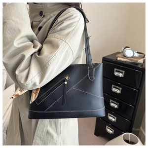 Close-up of black leather tote bag with white contrast stitching and decorative silk scarf