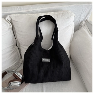Detailed macro view of black pleated fabric texture and Fashion label on tote bag