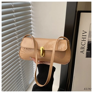 Detail of a beige patent leather underarm bag with a golden metal twist lock closure