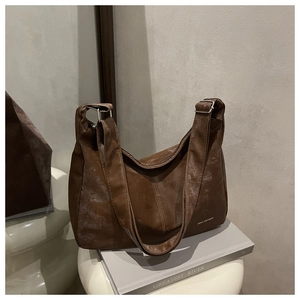 Detail of vintage brown leather hobo bag with white logo and silver metal buckle