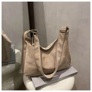 Detail of retro beige hobo bag in faux suede with adjustable silver buckle on a book