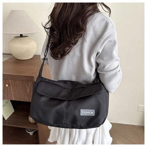 Detailed view of black nylon tote bag with Fashion label and adjustable shoulder strap
