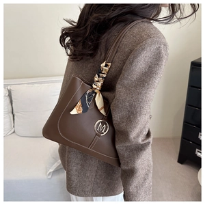 Detail of dark brown leather tote bag with white stitching and decorative silk scarf