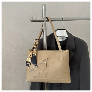 Detail of khaki leather tote bag with silk scarf handle decoration and diagonal stitching