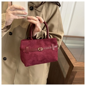 Detail of burgundy frosted suede handbag with vintage metal buckle and top handle