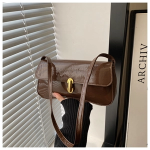 Detail of glossy brown faux leather shoulder bag featuring a golden twist-lock closure