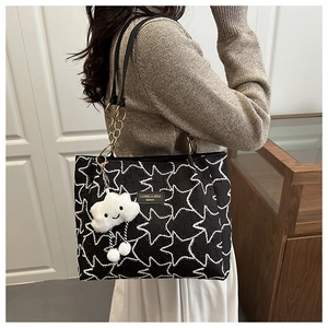Side view of black tote bag with white star patterns and plush cloud charm accessory
