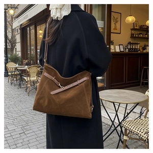 Detail of dark brown faux suede tote bag with belt accent on a wool coat outfit