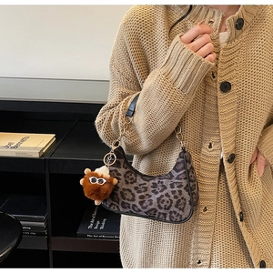 Detail of leopard print crescent bag with chain strap and brown faux fur pompom charm