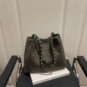 Sac cabas en daim à imprimé léopard vert avec poignées tressées sur une chaise