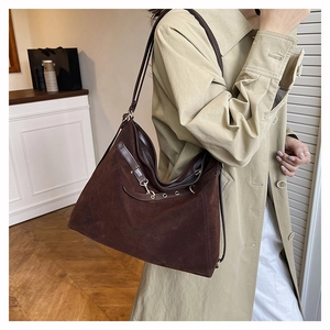 Deep brown matte suede tote bag with decorative buckle shown on a model in trench coat