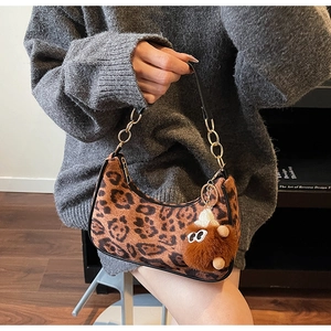 Close-up of leopard print hobo bag with gold chain strap and plush monster charm detail
