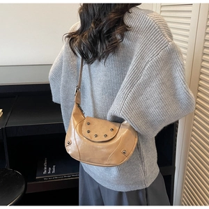 Sac bandoulière rétro en similicuir avec clous porté par un mannequin dans une pièce