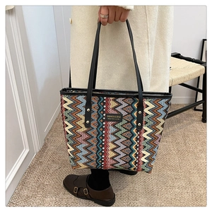 Close-up of a large woven tote bag with colorful zigzag patterns and metal rivets