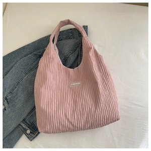 Detailed close-up of pink corduroy pleated fabric texture and white fashion label on tote