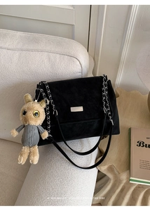 Detail of black matte leather crossbody bag with silver chain and cute bunny plush charm
