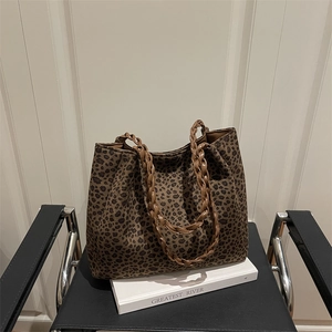 Grand sac cabas léopard en daim avec anses tressées marron sur une chaise moderne