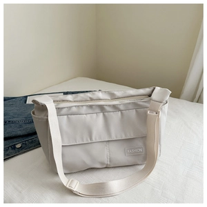Detail of off-white nylon crossbody bag showing the front flap pocket and fashion label
