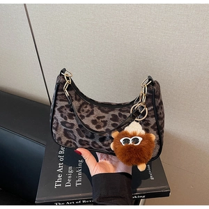 Close-up of leopard print baguette bag with black leather trim and plush charm