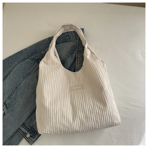 Detail of minimalist cream hobo bag with pleated texture and FASHION logo patch