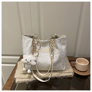 Detail of white quilted tote bag featuring gold chain strap and plush cloud charm