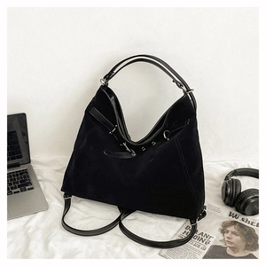 Macro detail of large black suede tote bag with leather handles and versatile straps