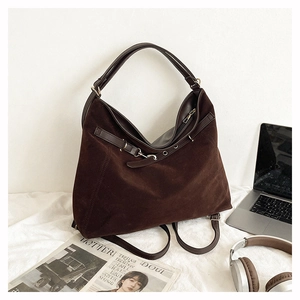 Detail of dark brown suede tote bag featuring adjustable side straps and metal buckles