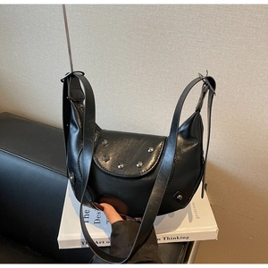 Détail du sac croissant en cuir noir avec des clous en métal vintage et une bandoulière réglable