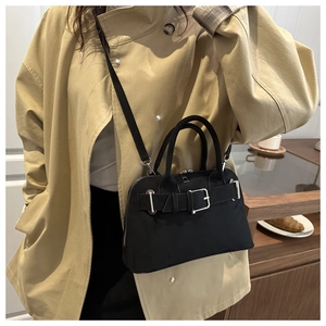 Detail of black minimalist handbag with silver buckle belt decor and dual handles
