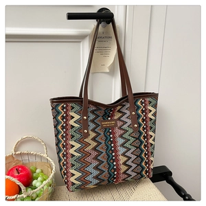 Detail of colorful zigzag woven tote bag with leather straps and metal brand logo plate